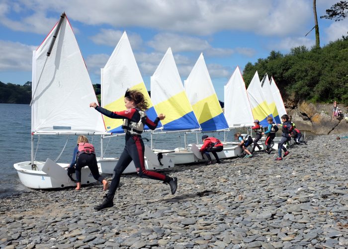 Happy child on the shore of Helford River with CST sailing boats